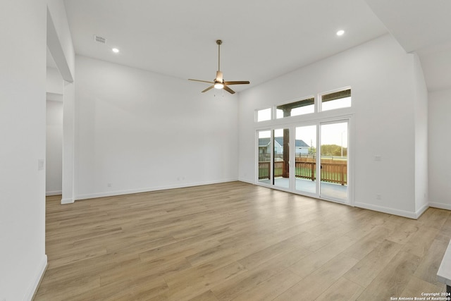 interior space with a high ceiling, light wood-type flooring, and ceiling fan