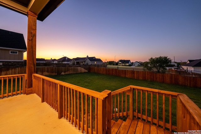 deck at dusk featuring a lawn