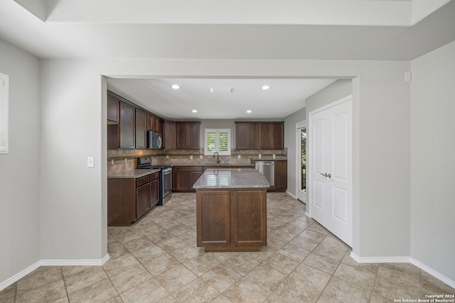 kitchen with light tile patterned flooring, a kitchen island, dark brown cabinetry, stainless steel appliances, and backsplash