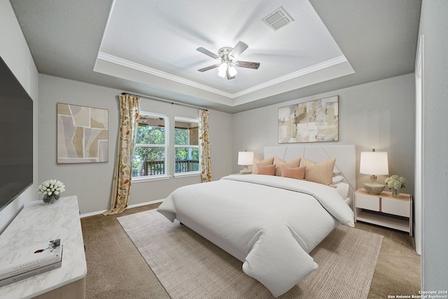 bedroom featuring ceiling fan, a tray ceiling, and carpet flooring