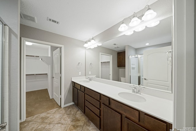 bathroom with walk in shower, vanity, and tile patterned flooring