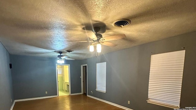 spare room with dark hardwood / wood-style flooring, ceiling fan, and a textured ceiling