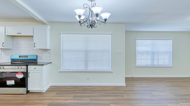 kitchen with a notable chandelier, stainless steel range with electric stovetop, white cabinetry, and hardwood / wood-style floors