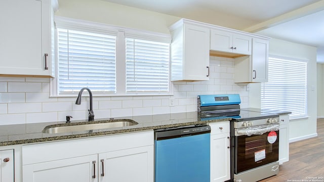 kitchen with light hardwood / wood-style flooring, dark stone countertops, sink, white cabinets, and appliances with stainless steel finishes