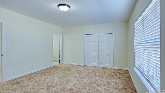 unfurnished bedroom featuring multiple windows, a closet, and light colored carpet