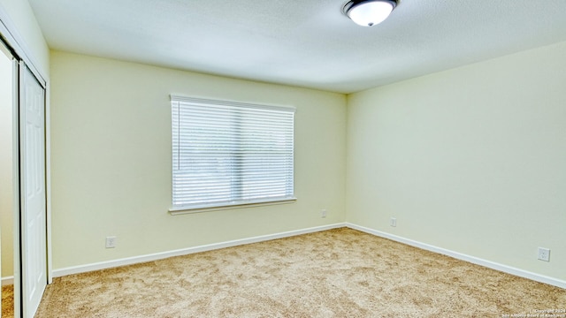 unfurnished bedroom with light carpet and a closet