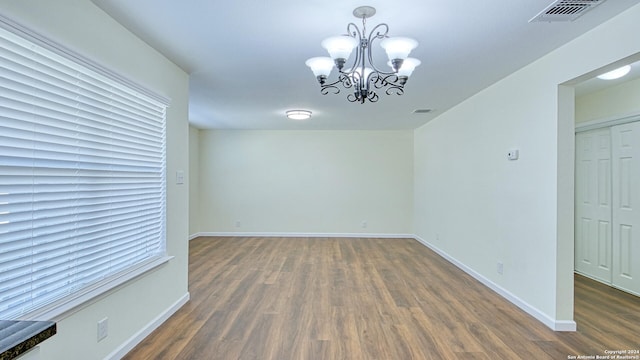 empty room featuring dark hardwood / wood-style floors and a notable chandelier