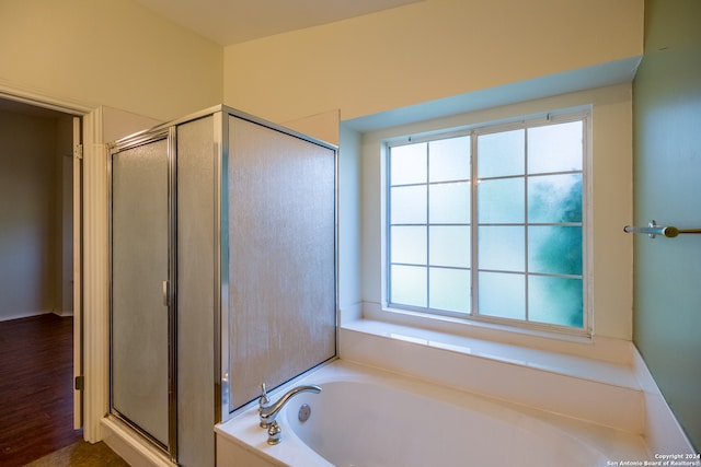 bathroom with hardwood / wood-style flooring, a wealth of natural light, and plus walk in shower