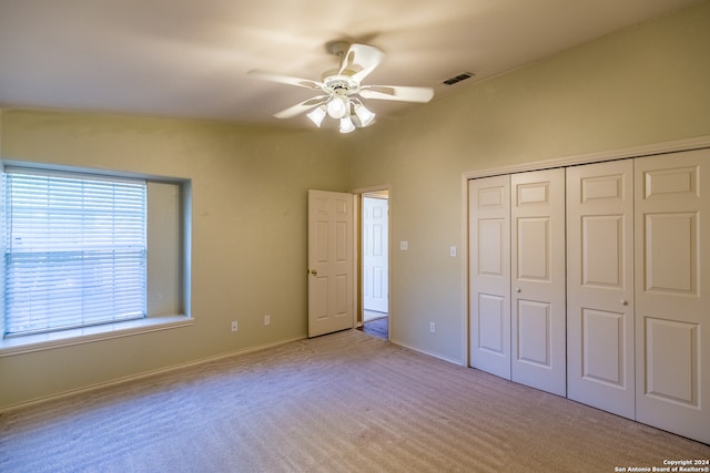 unfurnished bedroom with light carpet, ceiling fan, and a closet