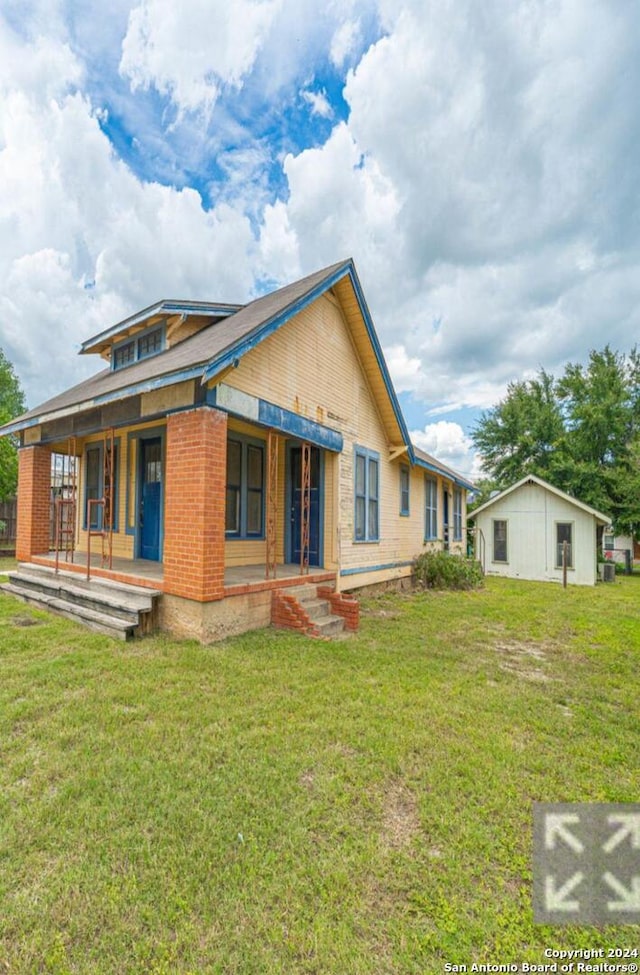 back of property featuring a yard and covered porch