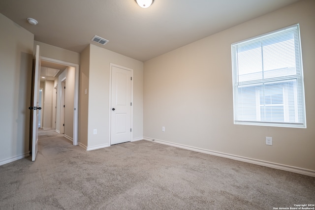 unfurnished bedroom with a closet and light colored carpet