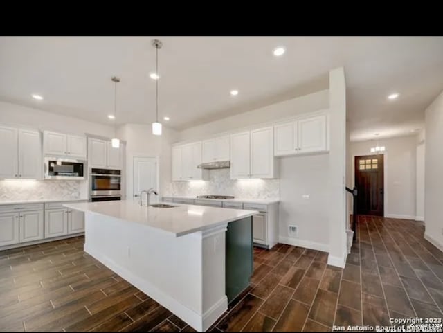 kitchen with a kitchen island with sink, sink, dark hardwood / wood-style flooring, and white cabinetry