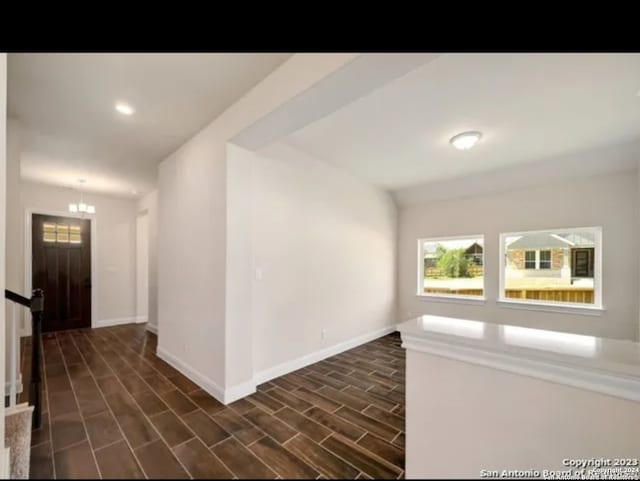 foyer entrance with an inviting chandelier and dark wood-type flooring