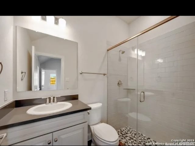 bathroom with vanity, toilet, and a shower with door