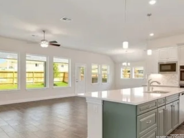 kitchen with a kitchen island with sink, ceiling fan, tasteful backsplash, built in microwave, and sink