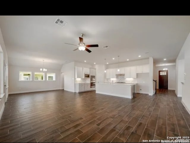 unfurnished living room with ceiling fan with notable chandelier and dark hardwood / wood-style floors