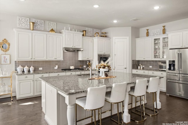 kitchen with dark wood-type flooring, white cabinetry, an island with sink, and stainless steel appliances