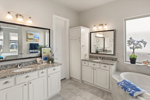 bathroom with tiled bath, ceiling fan, vanity, and tile patterned floors