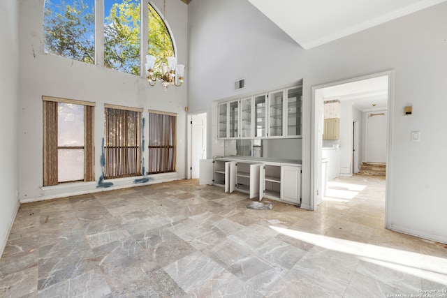 unfurnished living room featuring a towering ceiling and a notable chandelier