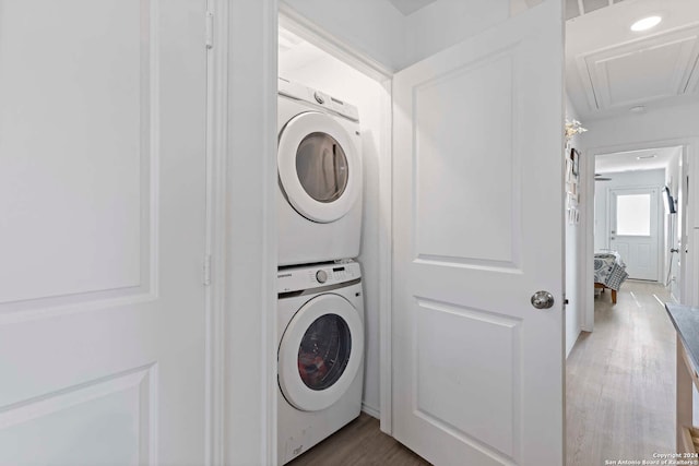 clothes washing area featuring stacked washer and clothes dryer and hardwood / wood-style flooring