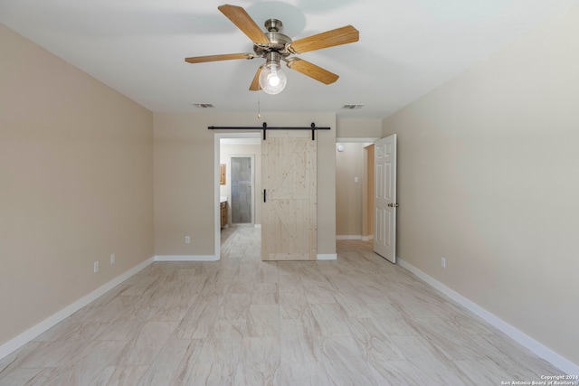 unfurnished bedroom featuring ceiling fan and a barn door