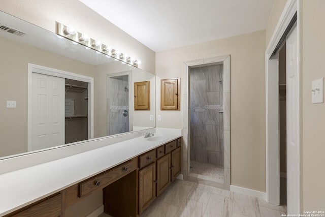 full bathroom with vanity, a tile shower, marble finish floor, and visible vents