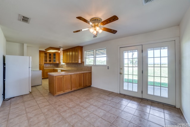 kitchen with ceiling fan, kitchen peninsula, french doors, backsplash, and white fridge