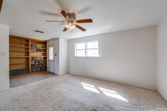 empty room featuring ceiling fan, a textured ceiling, and light carpet