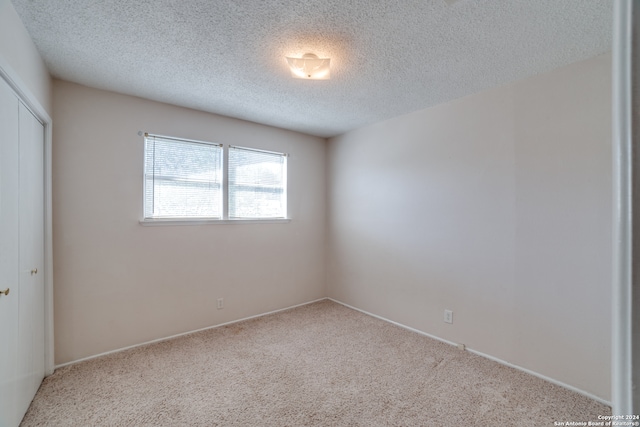 carpeted empty room featuring a textured ceiling