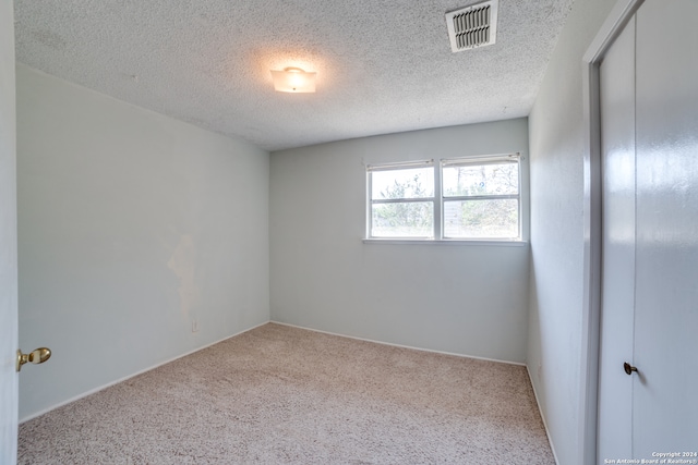 carpeted empty room featuring a textured ceiling