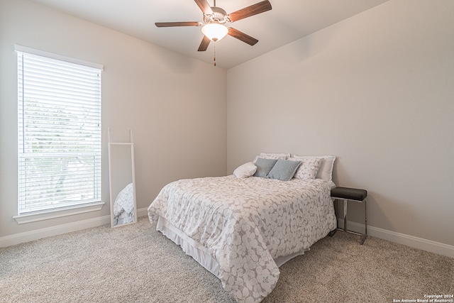 bedroom featuring ceiling fan, light carpet, and multiple windows