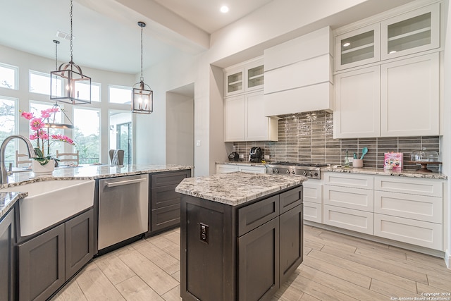 kitchen with white cabinets, hanging light fixtures, appliances with stainless steel finishes, a chandelier, and sink