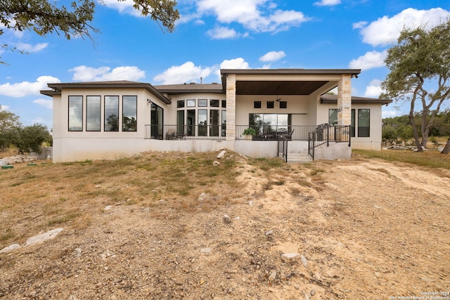 rear view of property featuring covered porch and ceiling fan