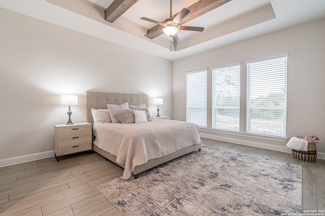 bedroom featuring beamed ceiling, a raised ceiling, light hardwood / wood-style floors, and ceiling fan