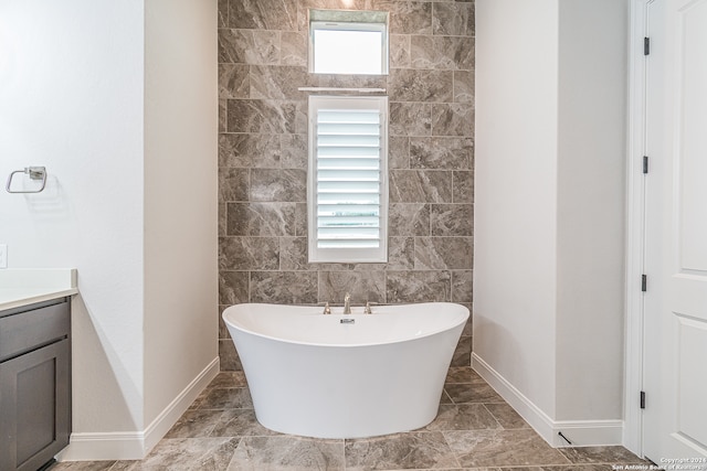 bathroom with vanity, a tub to relax in, and tile walls