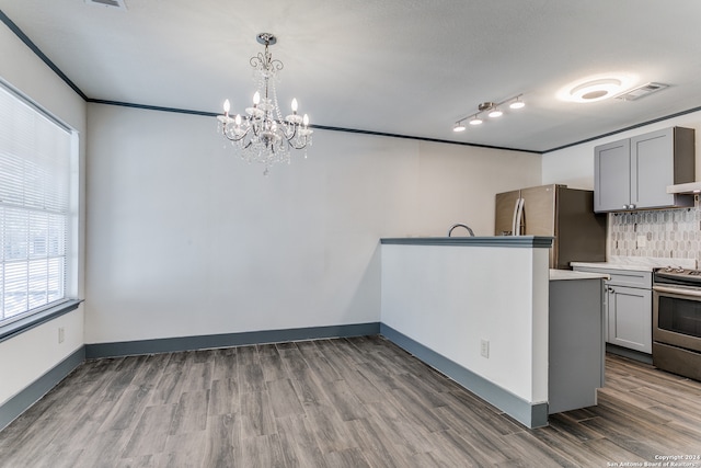 kitchen with appliances with stainless steel finishes, hardwood / wood-style flooring, gray cabinets, and tasteful backsplash