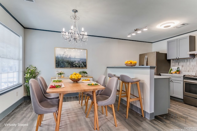 dining space featuring wood-type flooring, an inviting chandelier, and crown molding