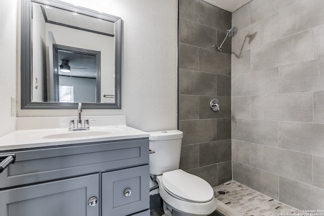 bathroom with tiled shower, vanity, and toilet