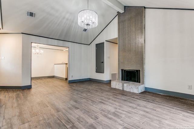 unfurnished living room with a large fireplace, wood-type flooring, beam ceiling, and a notable chandelier