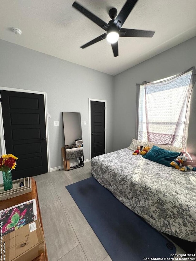 bedroom with light hardwood / wood-style flooring, a textured ceiling, and ceiling fan