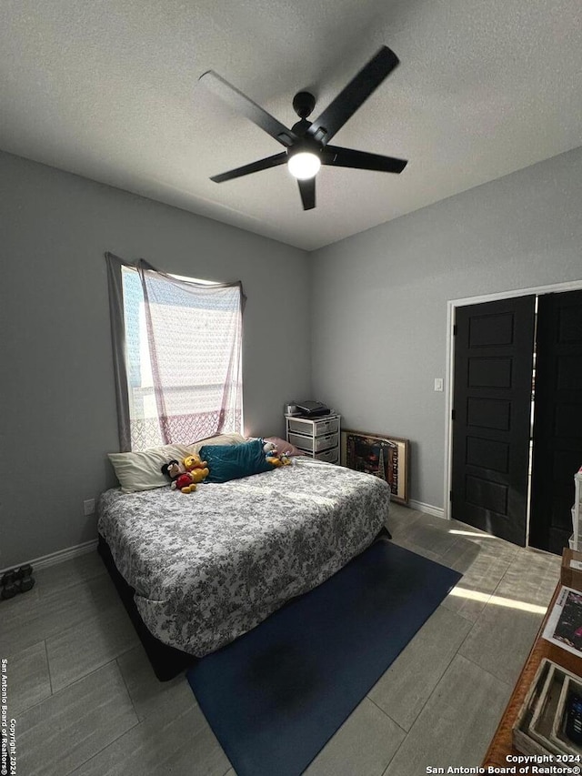 bedroom with ceiling fan and a textured ceiling