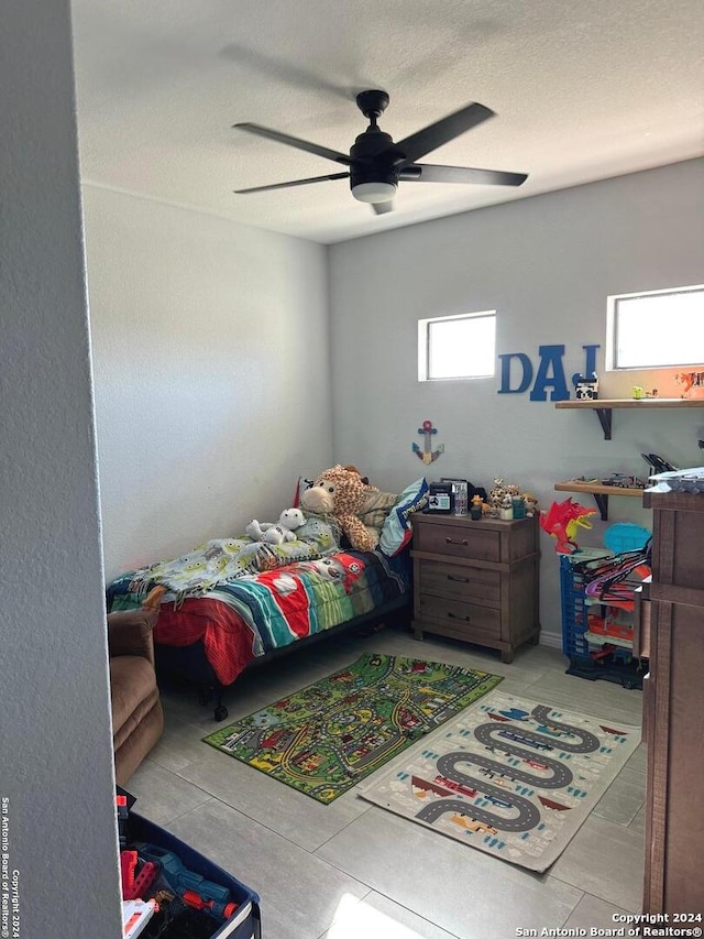 bedroom featuring ceiling fan, a textured ceiling, and multiple windows