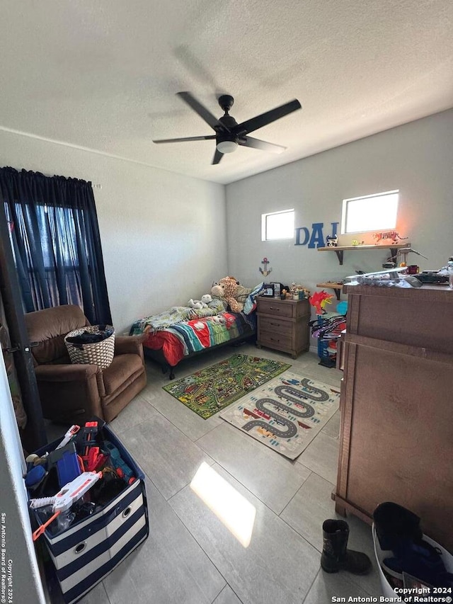 tiled bedroom with ceiling fan and a textured ceiling