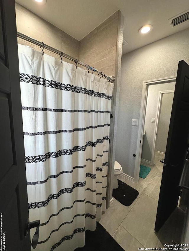 bathroom featuring tile patterned flooring, toilet, and a shower with curtain