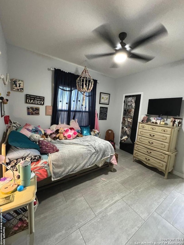 tiled bedroom with ceiling fan and a textured ceiling