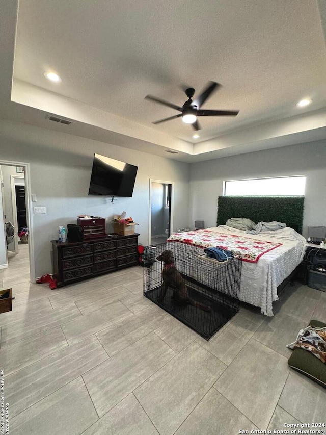 bedroom featuring ceiling fan, a raised ceiling, and a textured ceiling