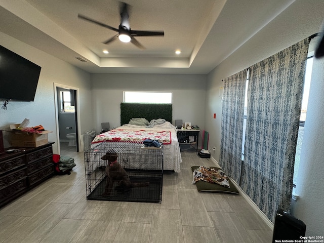 bedroom featuring ceiling fan, light hardwood / wood-style flooring, and a raised ceiling