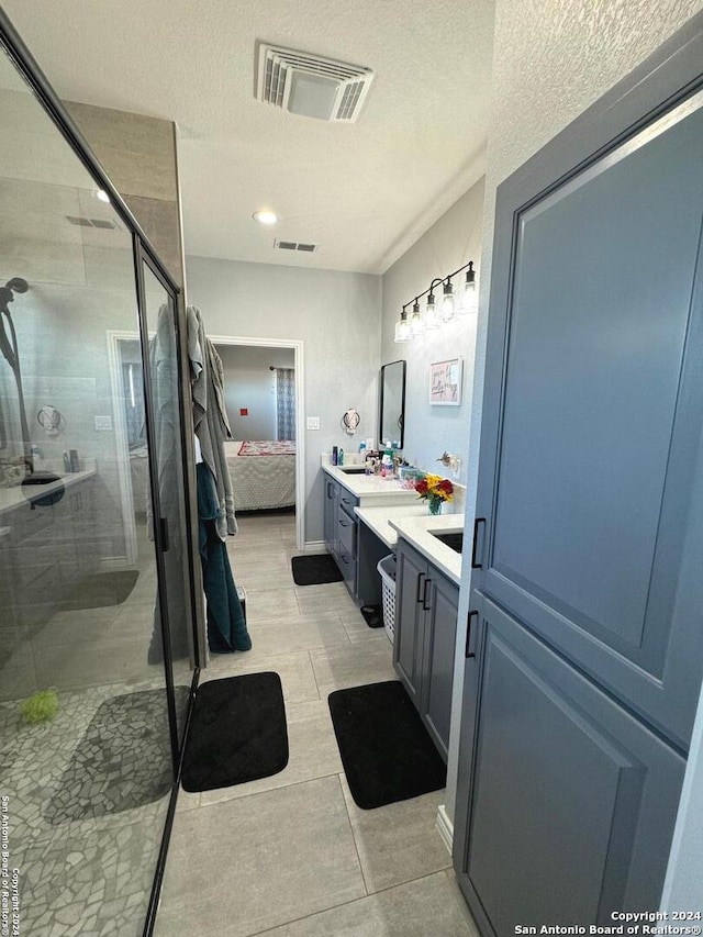 bathroom with a shower with door, vanity, and a textured ceiling