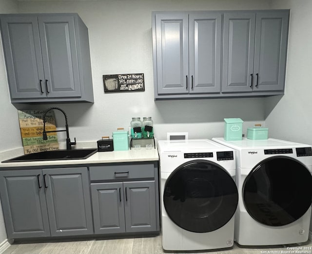 laundry room with light hardwood / wood-style flooring, separate washer and dryer, sink, and cabinets