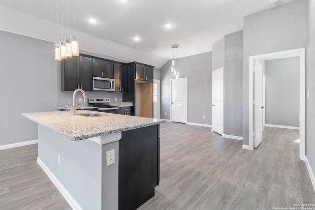 kitchen with light stone countertops, appliances with stainless steel finishes, hanging light fixtures, and sink